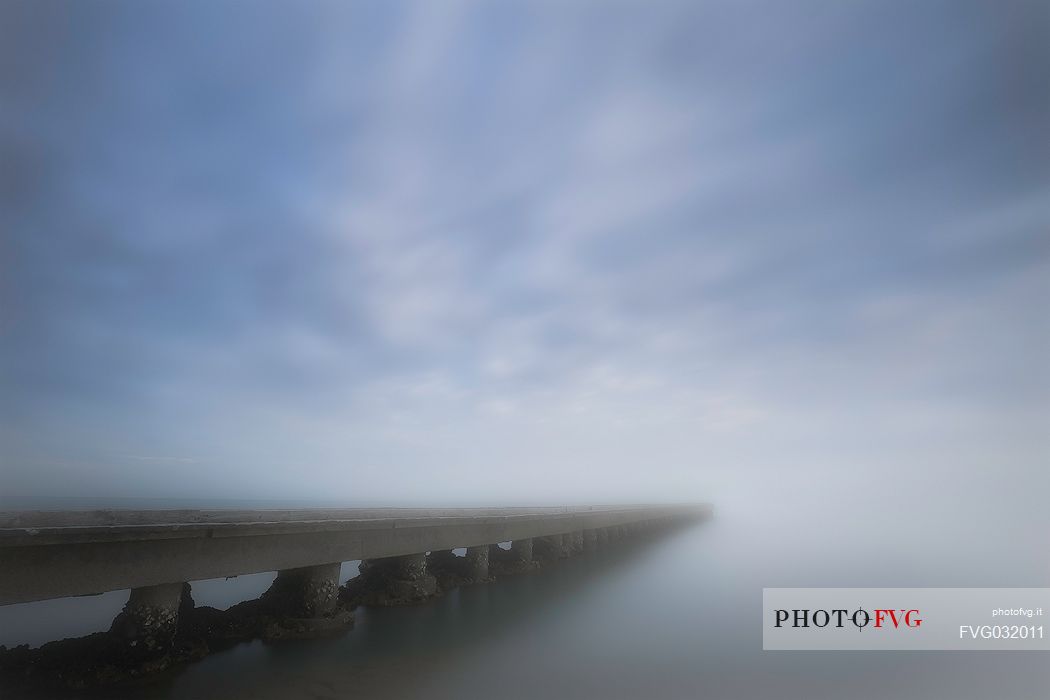 Pier in the mist in Caorle beach, Adriatic coast, Veneto, Italy

