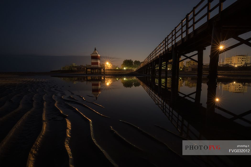 Pier and the old lighthouse by night in Lignano Sabbiadoro, Friuli Venezia Giulia, Italy