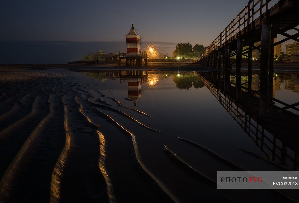 Pier and the old lighthouse by night in Lignano Sabbiadoro, Friuli Venezia Giulia, Italy