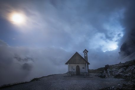 Alpine church wrapped by clouds at dusk, Tre Cime natural park, dolomites, Italy