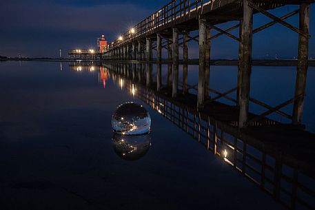 Lighthouse pier in Lignano Sabbiadoro mirrored in a cristal ball, Friuli Venezia Giulia, Italy