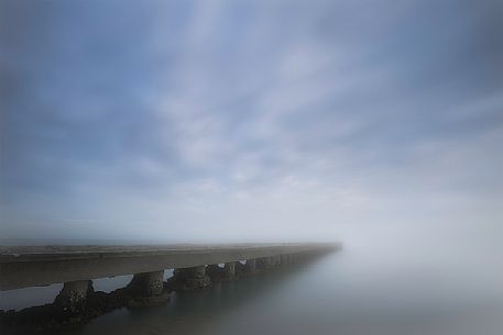 Pier in the mist in Caorle beach, Adriatic coast, Veneto, Italy

