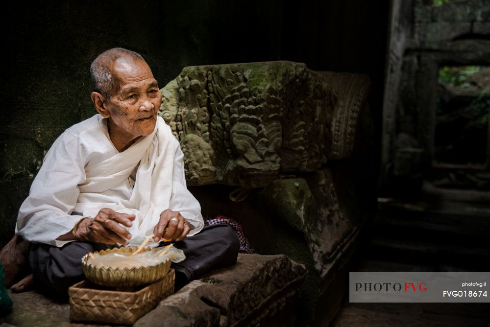 Old woman making bracelets in a Preah Kan temple