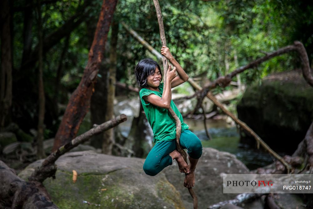 Happy girl hanging from a tree at Phnom Kulen National Park 