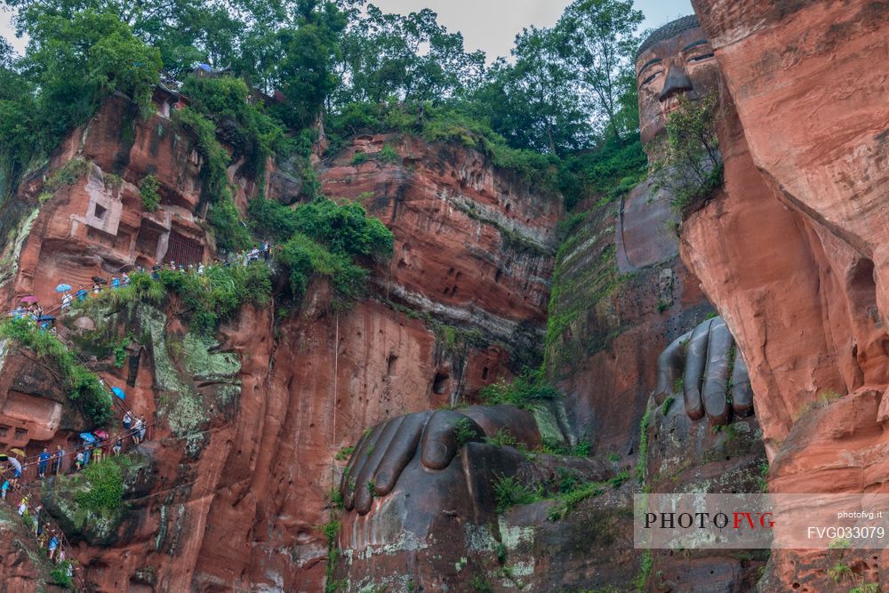 Tourists climb the cliff to admiring the Giant Buddha, the largest buddha of the world carved on Emei Shan, sacred mount, Leshan, Sichuan, China