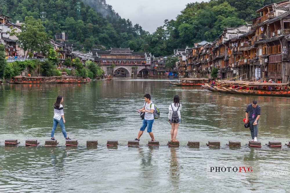 Tourist visiting the ancient village of Fenghuang along the Tuo Jiang River, in the background the Phoenix Hong bridge, Hunan, Cina