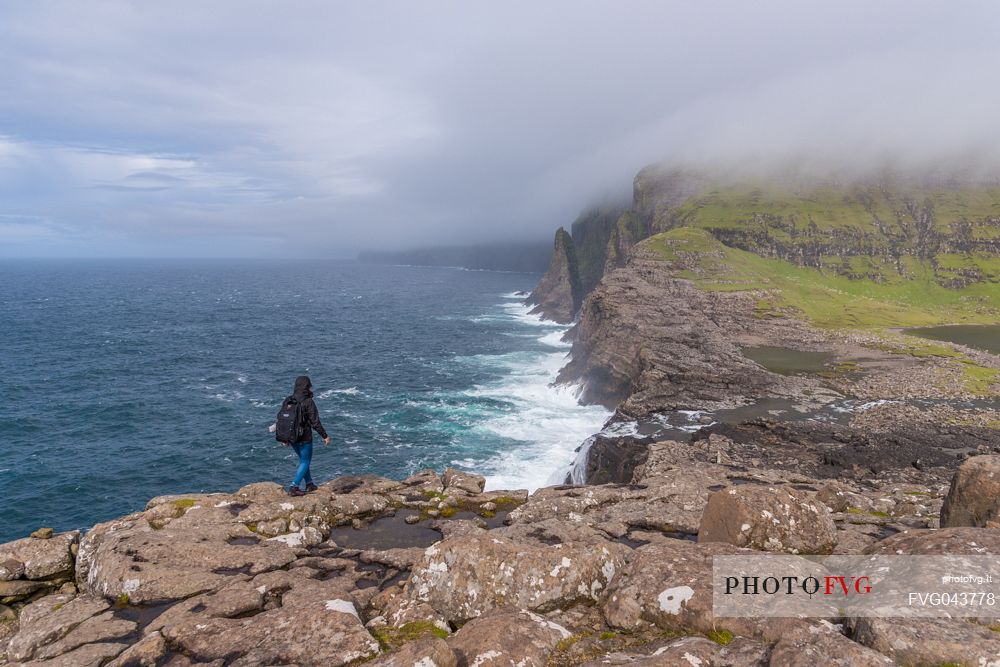 Tourist walkingo on the Srvgsvatn or  Leitisvatn cliffs, Faeroe Islands, Denmark, Europe