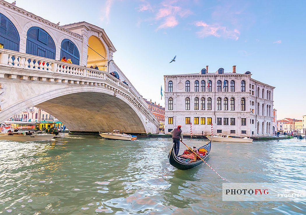 Gondola tourists in the  Canal Grande near Rialto Bridge, Ponte di Rialto in the background at sunset, Venice, Italy, Europe