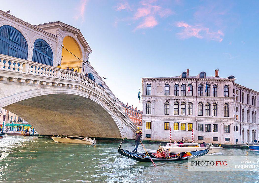 Gondola tourists in the  Canal Grande near Rialto Bridge, Ponte di Rialto in the background at sunset, Venice, Italy, Europe