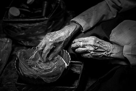 Old woman making bracelets in a Preah Kan temple