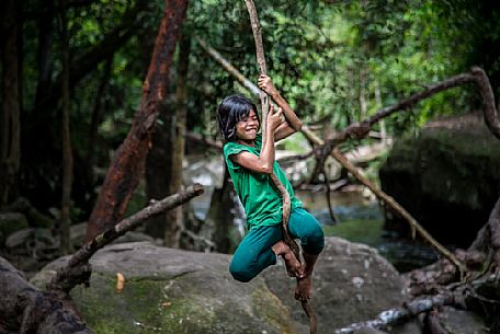 Happy girl hanging from a tree at Phnom Kulen National Park 