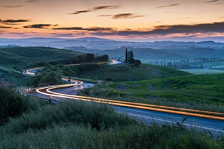 Crete Senesi landscapes, red car light trails on a road, Orcia valley, Tuscany, Italy Crete Senesi landscapes, red car light trails on a road, Orcia valley, Tuscany, Italy