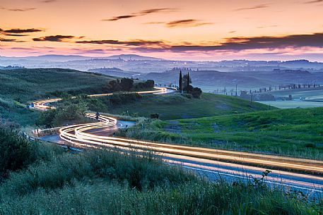 Crete Senesi landscapes, red car light trails on a road, Orcia valley, Tuscany, Italy Crete Senesi landscapes, red car light trails on a road, Orcia valley, Tuscany, Italy