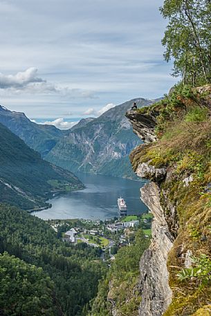 Girl relaxing on the Flydalsjuvet rock, over the Geiranger fjord, Norway Girl relaxing on the Flydalsjuvet rock, over the Geiranger fjord, Norway
