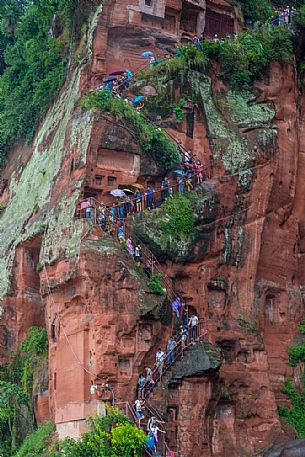 Tourists climb the cliff to admiring the Giant Buddha, the largest buddha of the world carved on Emei Shan, sacred mount, Leshan, Sichuan, China