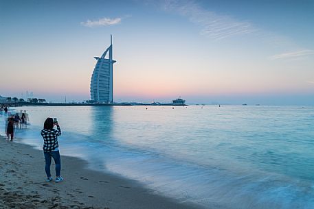 Tourist takes a picture at the Burj Al Arab Hotel from Jumeirah beach, at twilight Dubai, United Arab Emirates, Asia