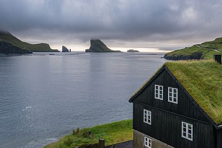 Traditional house in the village of Bur, near Srvgur, with the islet of Tindhlmuron the horizon, Vagar Island, Faeroe island, Denmark, Europe