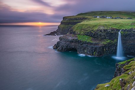 Coast with Múlafossur waterfall and the village of Gĺsedal or Gásadalur, Vágar Island (Vĺgř), Faeroe Islands, Denmark, Europe Coast with Múlafossur waterfall and the village of Gĺsedal or Gásadalur, Vágar Island (Vĺgř), Faeroe Islands, Denmark, Europe