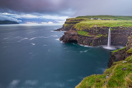 Coast with Múlafossur waterfall and the village of Gĺsedal or Gásadalur, Vágar Island (Vĺgř), Faeroe Islands, Denmark, Europe Coast with Múlafossur waterfall and the village of Gĺsedal or Gásadalur, Vágar Island (Vĺgř), Faeroe Islands, Denmark, Europe