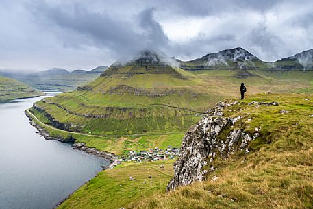 Tuurist admires the Funningur fjord, Eysturoy Island, Faeroe islands, Denmark, Europe Tuurist admires the Funningur fjord, Eysturoy Island, Faeroe islands, Denmark, Europe