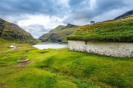 Tyical house and church in the background near Saksun village, Streymoy island, Faeroe islands, Denmark, Europe