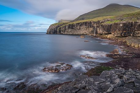 Wild coast and waterfall near Eiði village, Eysturoy island, Faeroe island, Denmark, Europe Wild coast and waterfall near Eiði village, Eysturoy island, Faeroe island, Denmark, Europe