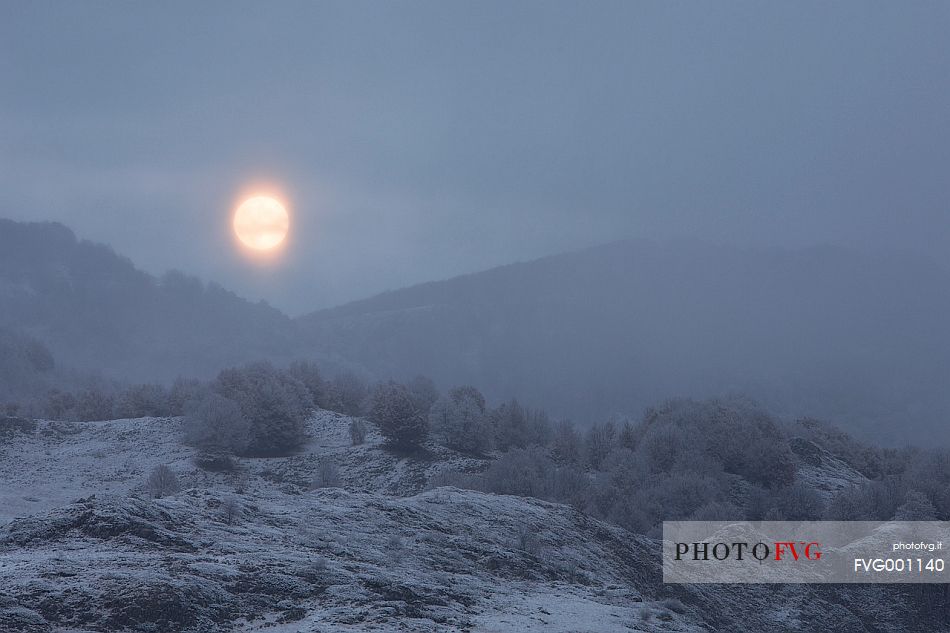 The full moon appears through the clouds after a heavy snowfall, Campo Imperatore, Gran Sasso national park