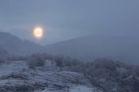 The full moon appears through the clouds after a heavy snowfall, Campo Imperatore, Gran Sasso national park