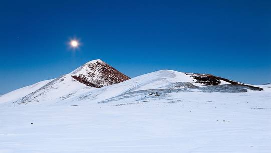 As a cold Arctic sun full moon rises from the top of the mountain Bolza.
