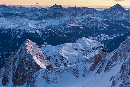 Sunrise from Punta Penia, the highest peak of Dolomites, in the Marmolada mountain group with Serauta hut lighting, Italy