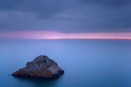 The Scoglo of the Dead is a cliff that rises from the sea just off the south west coast of Sardinia. Here it is taken at sunset, Nebida, Sulcis-Iglesiente, Sardinia, Italy