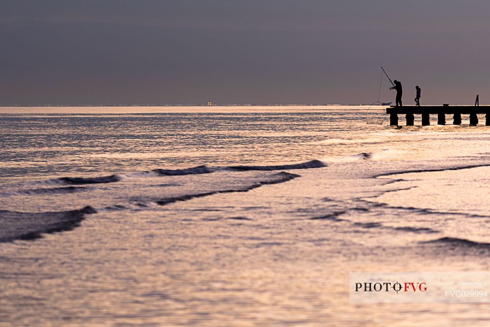 Fisherman on the dock at sunset, Lido di Jesolo, Venice, Italy.