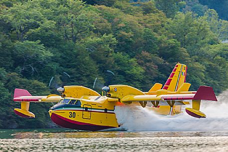 Firefighting airplane, Bombardier 415 - Canadair CL-415, taking water from the Lake, Somplago, Cavazzo Carnico, Udine, Italy. 