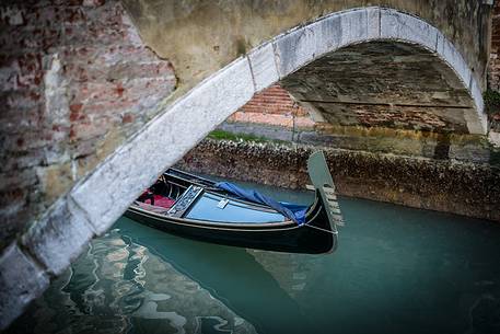 Detail of old gondola under the bridge on the canal in Venice, Veneto, Italy, Europe
