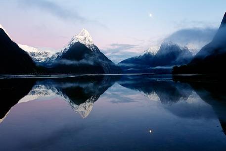 Moon and snow capped peaks reflected on the sound during an amazing sunrise in Fiorland Region.