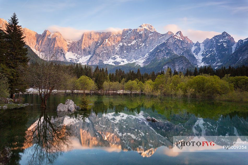 Sunset on Fusine lake, Mount Mangart mountain range reflected on the lake