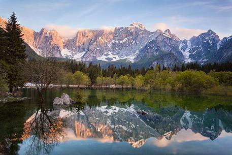 Sunset on Fusine lake, Mount Mangart mountain range reflected on the lake