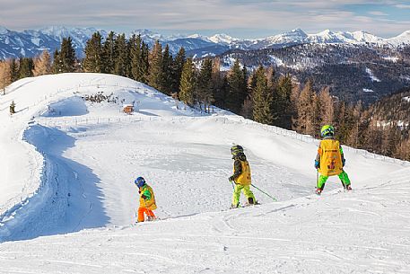 Three little children at the ski lesson in the piste of Biospharenpakbahn Brunnach, Nockberge mountain area, Bad Kleinkirchheim, Carinthia, Austria, Europe