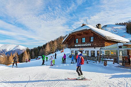 Skiers in front of Maibrunnhütte mountian hut on the top of Maibrunnbahn alpine station, Bad Kleinkirchheim, Carinthia, Austria, Europe