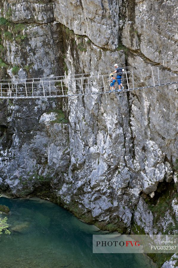 Father and son have fun on a suspension bridge in the park of the Friuli Dolomites above the river Cellina, Barcis, Friuli Venezia Giulia, Italy