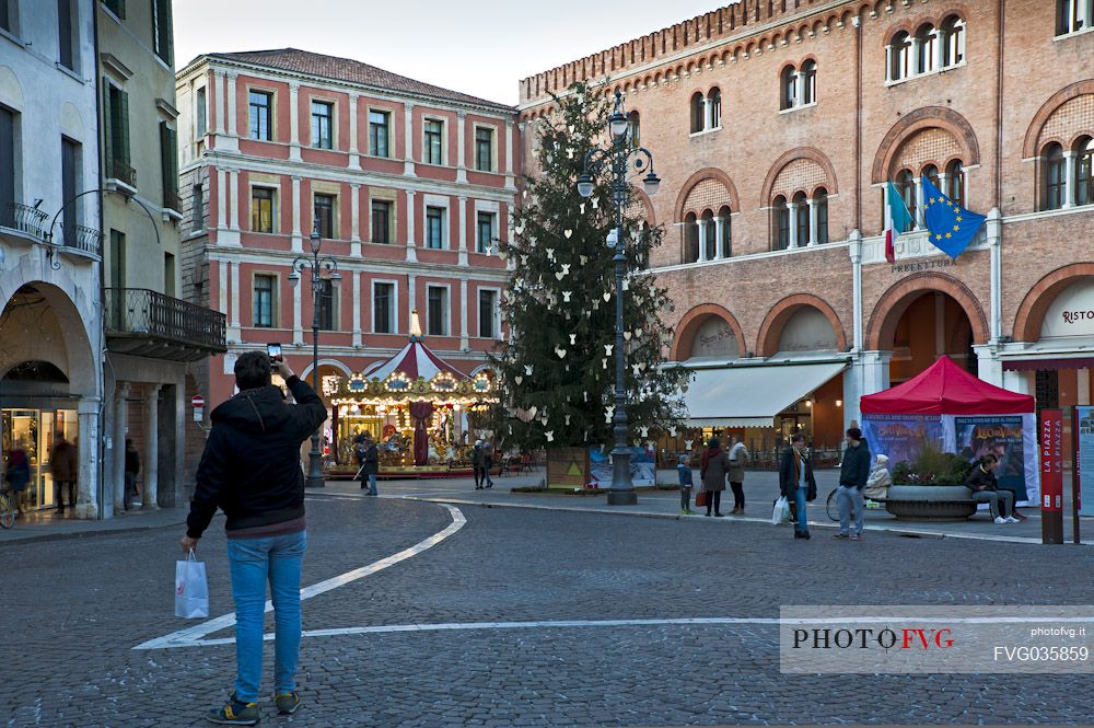 A man photographs the Piazza dei Signori and the Christmas tree in Treviso, Veneto Italy, Europe