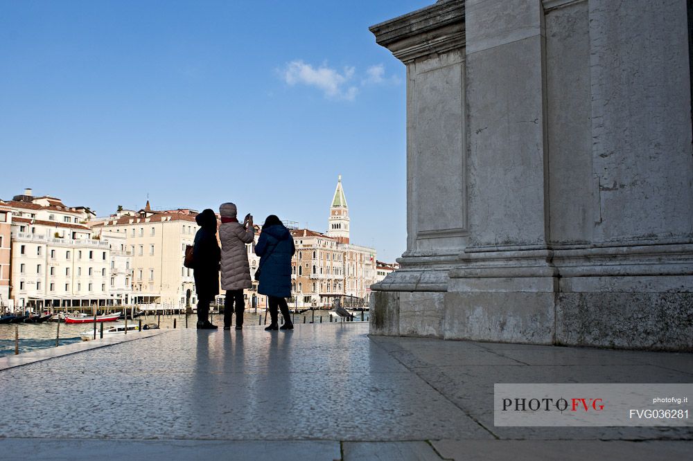 Turists take pictures of the bell tower of San Marco from the churchyard of the Basilica of the Madonna della Salute in the Dorsoduro district of Venice, Italy, Europe