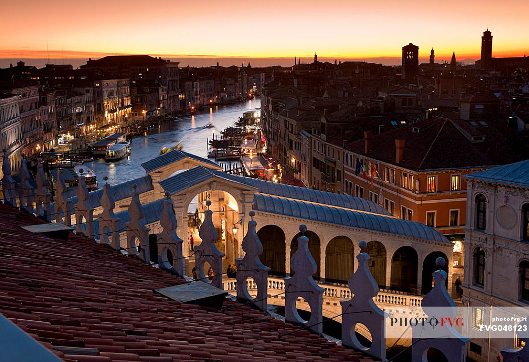 The famous Rialto bridge rises over the Grand Canal in Venice illuminated by the evening lights, Italy, Europe