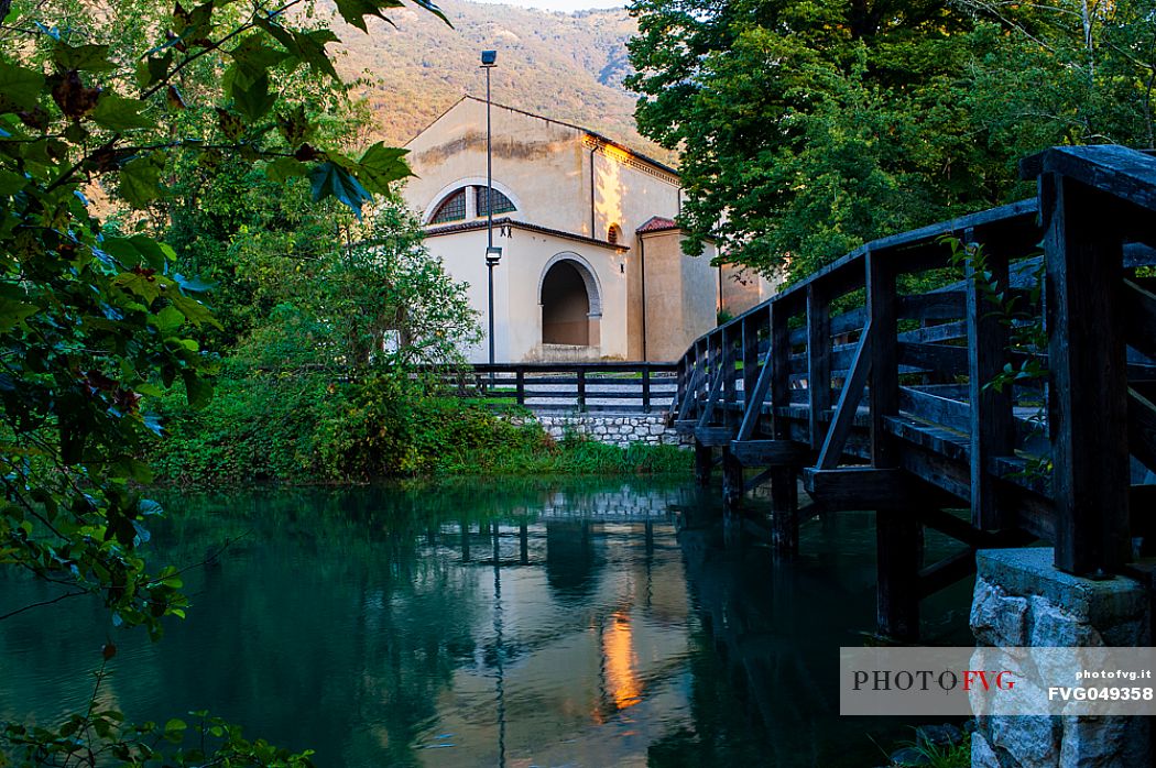 The sanctuary of the Holy Trinity in Polcenigo is reflected in the waters of the Livenza river near its source. Italy