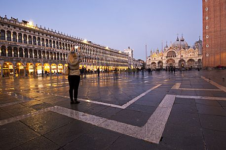 Tourist photographs the Basilica of St. Mark in Venice at twilight, Italy