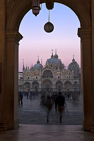 Tourists in Saint Mark Square admire the cathedral at sunset, Venice. Italy