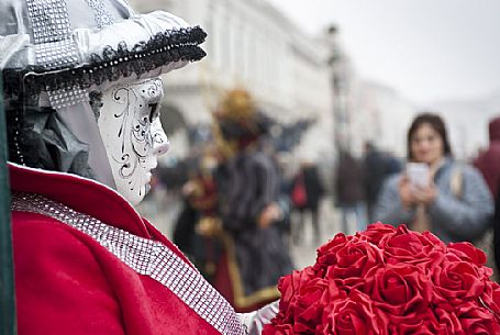 A tourist takes a picture of a colored mask in Saint Mark Square in Venice. Italy