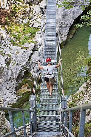 A girl has fun on a suspension bridge in the park of the Friuli Dolomites above the river Cellina, Barcis, Friuli Venezia Giulia, Italy