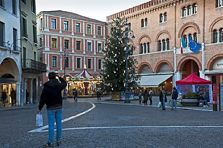 A man photographs the Piazza dei Signori and the Christmas tree in Treviso, Veneto Italy, Europe
