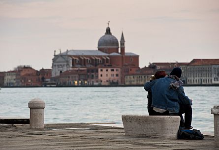 Engaged couple observe the Church of the Redeemer from the foundations of the Zattere or rafts in Venice, Italy, Europe